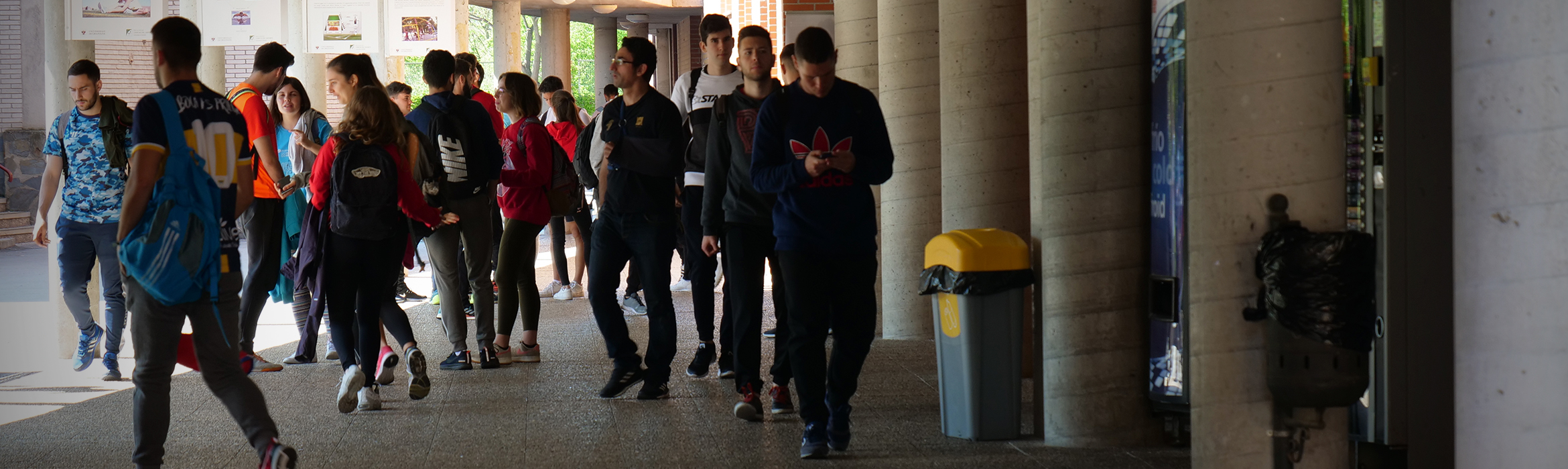 Estudiantes de la Facultad de Ciencias del Deporte caminando por zonas exteriores techadas entre edificios.