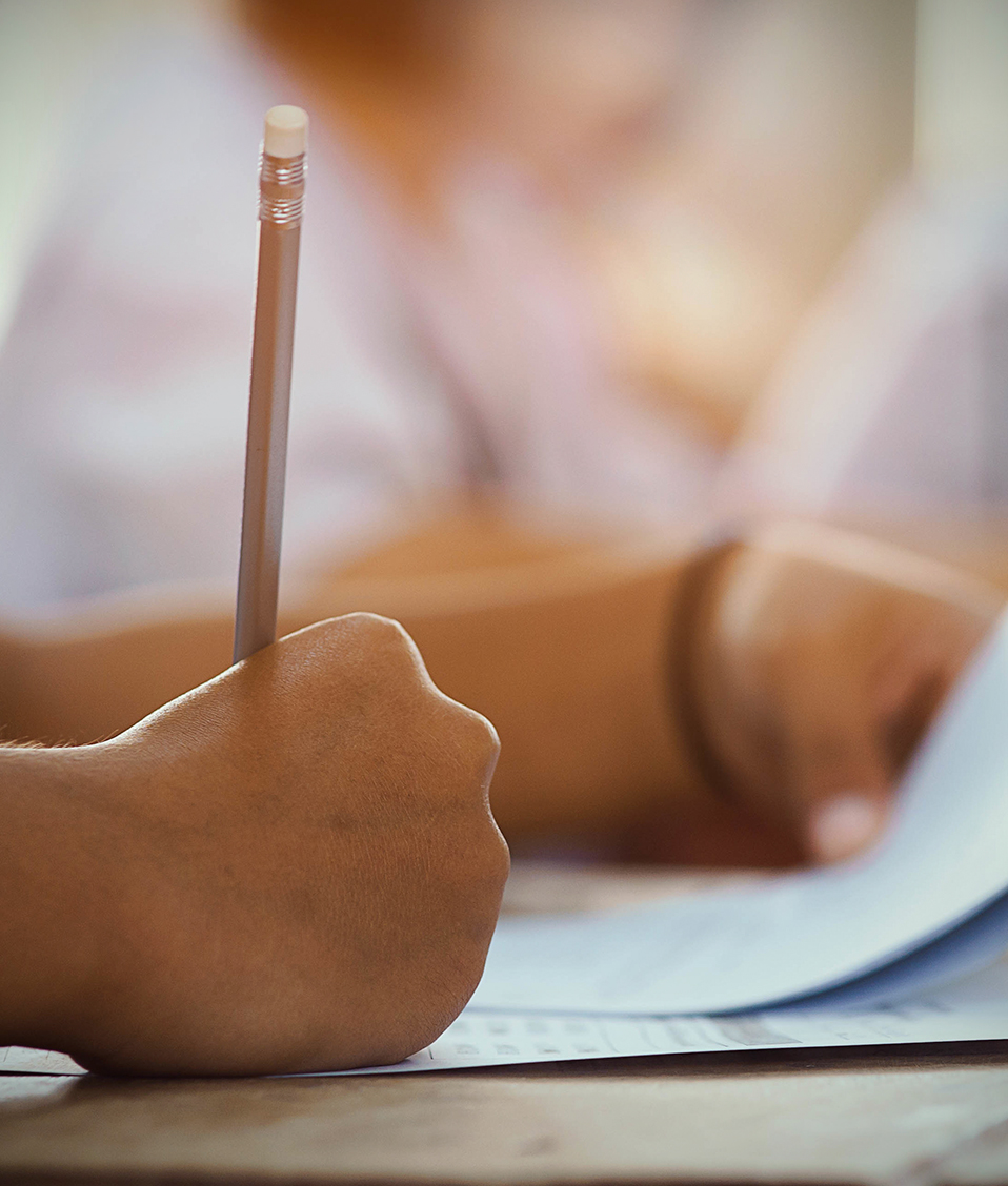 Un estudiante escribe a lápiz sobre diversos folios